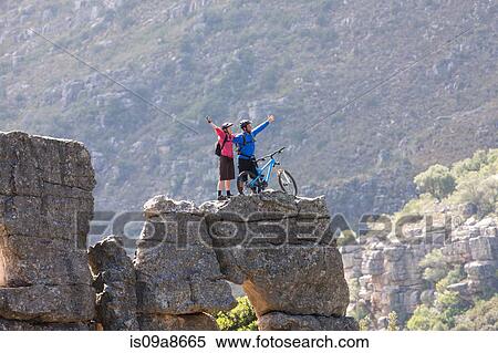 Mountain biking couple celebrating on rock formation View Large Photo Image Stock Photography - Mountain biking couple celebrating on rock formation. Fotosearch