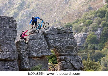 Picture - Mountain biking couple climbing rock formation. Fotosearch