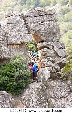 Stock Photo - Mountain biking couple kissing on rock formation. Fotosearch