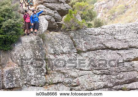 Mountain biking couple looking out from rock formation View Large Photo Image Stock Photograph - Mountain biking couple looking out from rock formation. Fotosearch