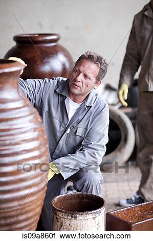 Stock Image - Painting and staining process in pottery factory. Fotosearch