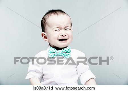 Stock Image - Portrait of baby boy wearing shirt and bow tie, crying. Fotosearch