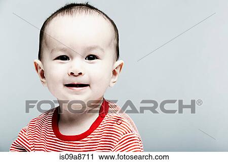 Stock Image - Portrait of baby boy wearing striped top looking at camera. Fotosearch