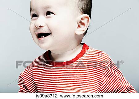 Stock Image - Portrait of baby boy wearing striped top looking away. Fotosearch