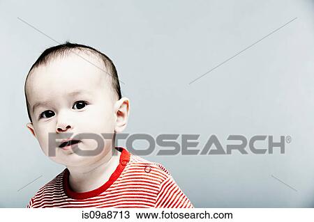 Stock Image - Portrait of baby boy wearing striped top looking at camera. Fotosearch
