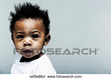 Stock Image - Portrait of baby boy wearing white looking at camera. Fotosearch