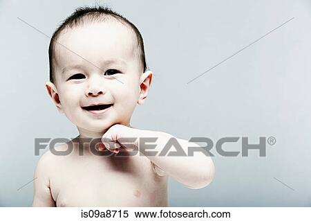 Stock Photography - Portrait of baby boy with hand on chin looking at camera. Fotosearch