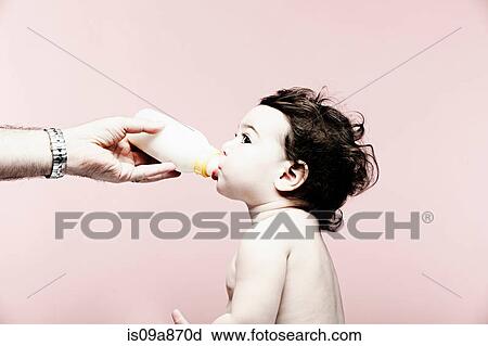 Stock Image - Portrait of baby girl drinking milk from bottle. Fotosearch