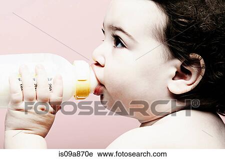 Stock Image - Portrait of baby girl drinking milk from bottle. Fotosearch