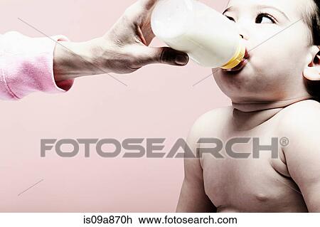 Stock Image - Portrait of baby girl drinking milk from bottle. Fotosearch