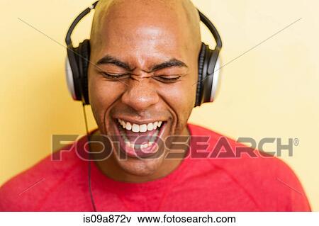 Stock Photo - Portrait of mid adult male singing with headphones. Fotosearch