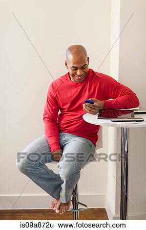Stock Photograph - Portrait of mid adult male with smartphone. Fotosearch