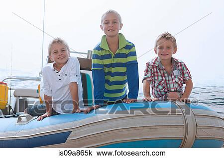 Portrait of three young boys at sea in dinghy View Large Photo Image Stock Image - Portrait of three young boys at sea in dinghy. Fotosearch