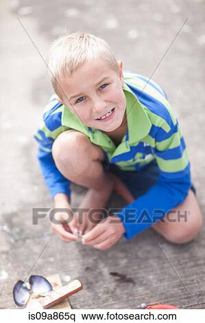 Stock Photography - Portrait of young boy sitting on pier with seashell. Fotosearch