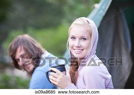 Stock Photography - Portrait of young couple sitting outside tent. Fotosearch