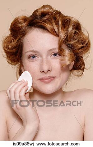 Stock Image - Portrait of young woman cleaning face with cotton wool. Fotosearch