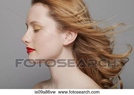 Stock Photo - Profile of young woman with curly red hair wearing make up. Fotosearch