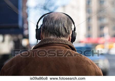 Stock Photo - Rear view of senior man wearing headphones. Fotosearch