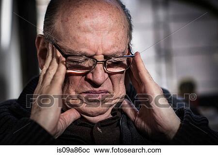 Stock Image - Senior man with eyes closed, wearing glasses, looking stressed. Fotosearch