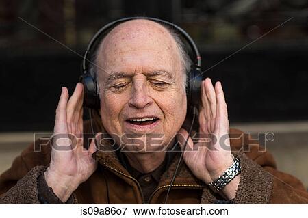 Stock Photo - Senior man with eyes closed wearing headphones. Fotosearch