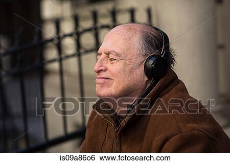 Stock Photograph - Senior man with eyes closed wearing headphones. Fotosearch
