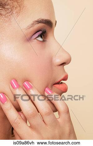 Stock Image - Side view of woman wearing make up and nail polish. Fotosearch