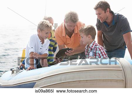 Stock Image - Small group of young men and young boys sea fishing in dinghy. Fotosearch