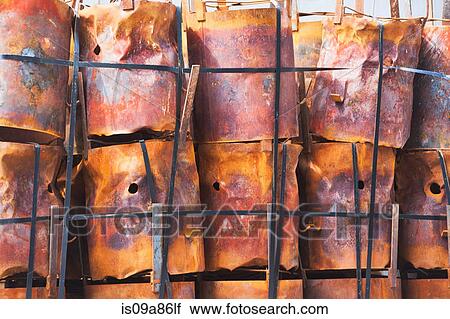 Stock Image - Stacked rusting barrels in a row. Fotosearch