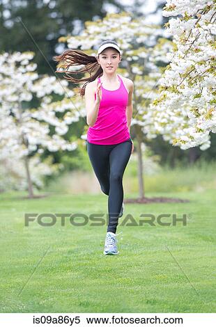 Stock Photography - Teenage girl wearing pink sportswear running in park. Fotosearch