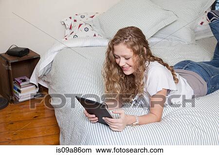 Teenager on bed, reading digital tablet View Large Photo Image Picture - Teenager on bed, reading digital tablet. Fotosearch