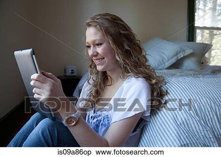 Teenager on bed, reading digital tablet View Large Photo Image Stock Photography - Teenager on bed, reading digital tablet. Fotosearch