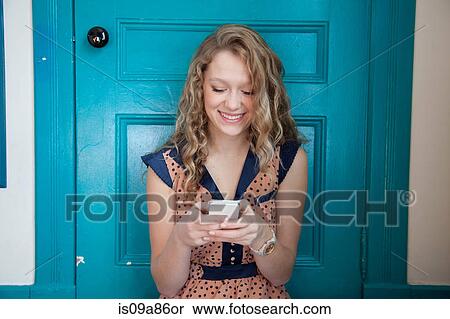 Teenager sitting in front of blue door, using mobile telephone View Large Photo Image Stock Photography - Teenager sitting in front of blue door, using mobile telephone. Fotosearch