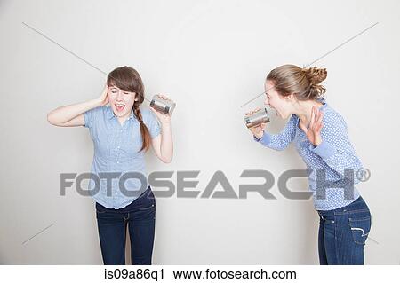 Two girls with tin cans, one shouting and one covering her ear View Large Photo Image Stock Image - Two girls with tin cans, one shouting and one covering her ear. Fotosearch