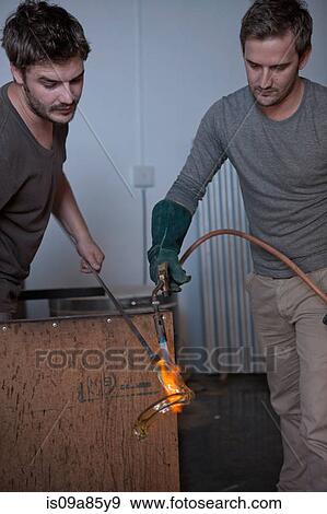 Stock Photo - Two men heating glass in factory. Fotosearch