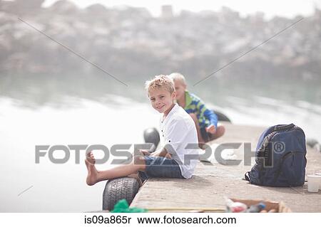 Two young boys sitting on pier fishing View Large Photo Image Stock Photography - Two young boys sitting on pier fishing. Fotosearch