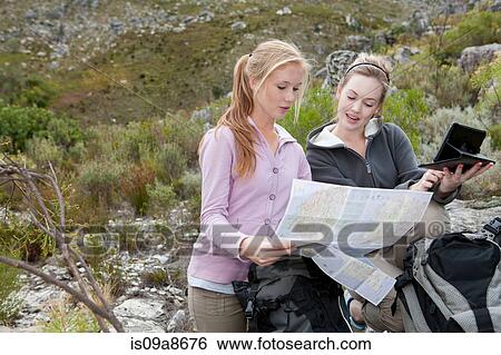 Two young female hikers looking at map View Large Photo Image Stock Photograph - Two young female hikers looking at map. Fotosearch