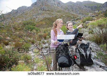 Two young female hikers with map and backpack View Large Photo Image Stock Photo - Two young female hikers with map and backpack. Fotosearch