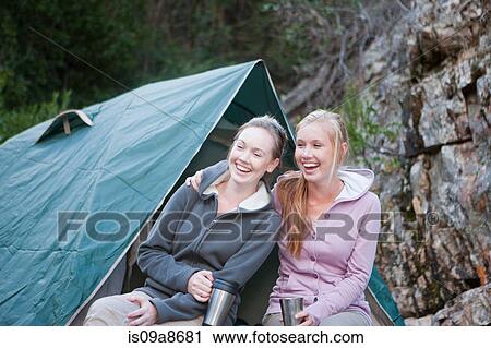 Stock Image - Two young girls sitting in front of tent. Fotosearch
