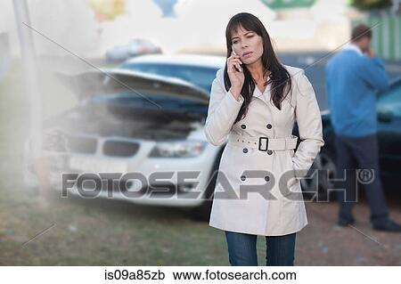 Stock Image - Woman on mobile phone after car accident. Fotosearch