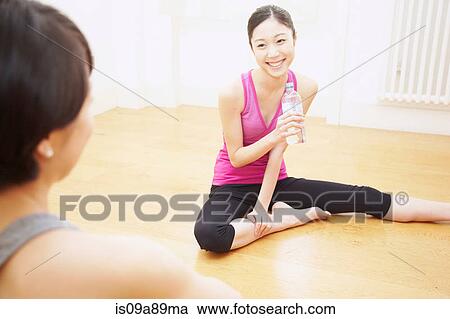 Stock Image - Woman sitting on floor with water bottle. Fotosearch