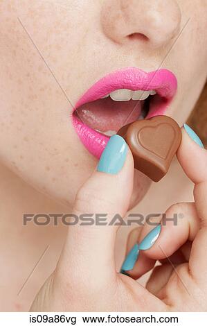 Woman wearing pink lipstick eating heart shaped chocolate View Large Photo Image Stock Image - Woman wearing pink lipstick eating heart shaped chocolate. Fotosearch