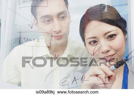 Stock Image - Woman writing on glass with marker pen. Fotosearch