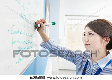 Stock Image - Woman writing on white board. Fotosearch