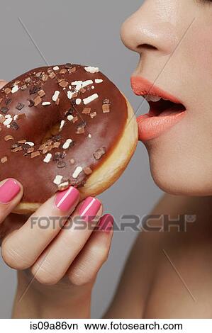 Young adult woman eating doughnut View Large Photo Image Picture - Young adult woman eating doughnut. Fotosearch