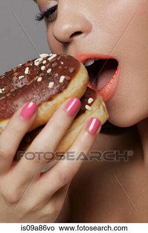 Young adult woman eating two doughnuts View Large Photo Image Picture - Young adult woman eating two doughnuts. Fotosearch