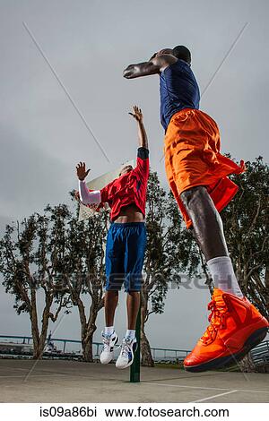Stock Image - Young basketball players jumping to score. Fotosearch