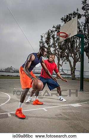Stock Image - Young basketball players playing on court. Fotosearch