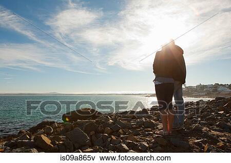 Stock Photo - Young couple looking out to sea and horizon. Fotosearch