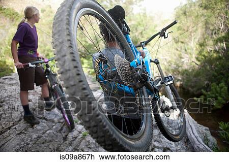 Stock Image - Young couple with mountain bikes on rock. Fotosearch
