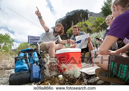Picture - Young group of hikers taking a break and checking direction. Fotosearch